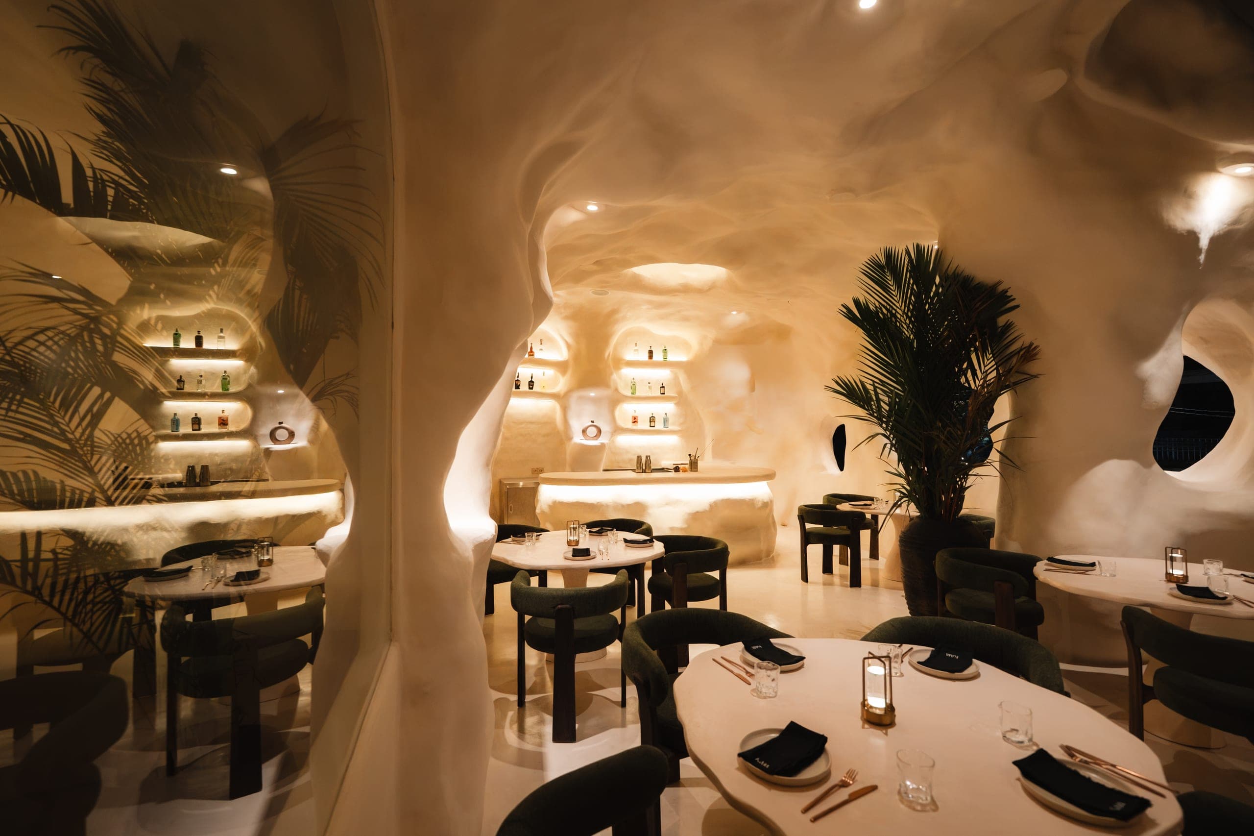 The KAJA dining room and bar: sculpted plaster walls, backlit shelves and set tables